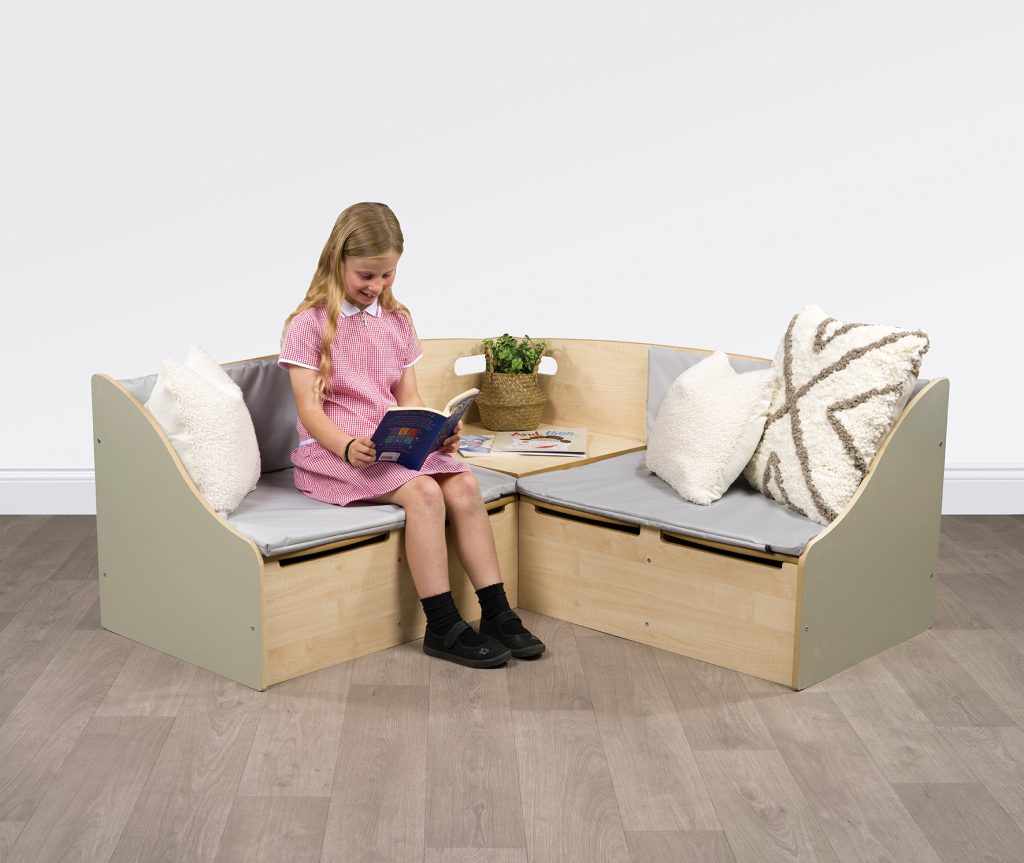 Primary school reading corner with soft seating and book storage in UK classroom
